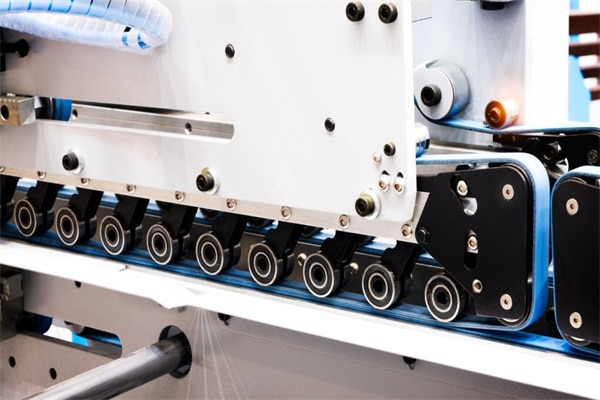 Fragment of the conveyor of sticking labeling machine. Abstract industrial background.