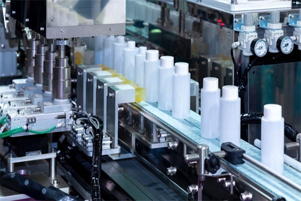 white plastic bottle moving on conveyor belt of auto capping and labeling machine at cosmetic and skin care manufacturing. cosmetic industry and ai technology machinery concept.